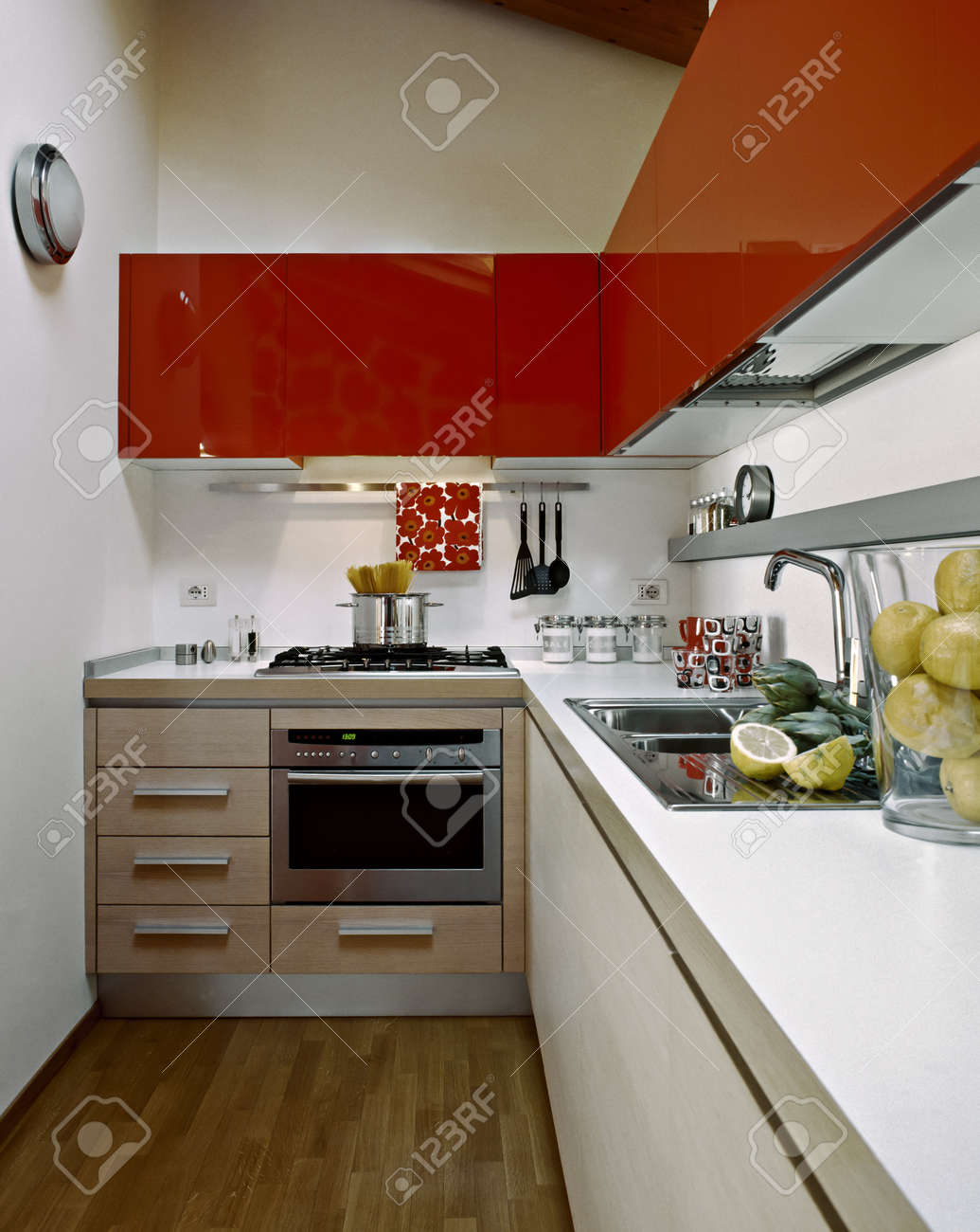 Moderne keuken met rode kasten in een zolderkamer met houten vloer ...