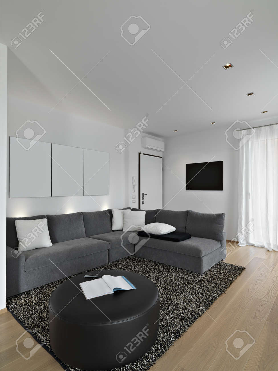Vävnads soffa i ett modernt vardagsrum med trägolv och matta ...