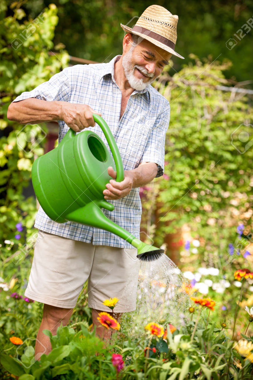 14298407-Senior-man-watering-the-flowers-in-the-garden-Stock-Photo-man.jpg