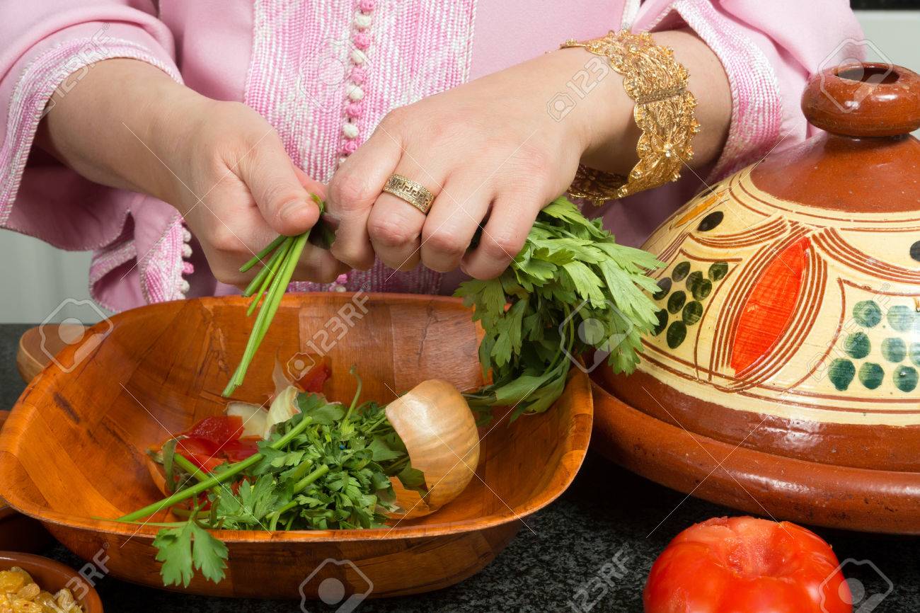 Mains d'une femme en ajoutant les légumes dans un tajine ...