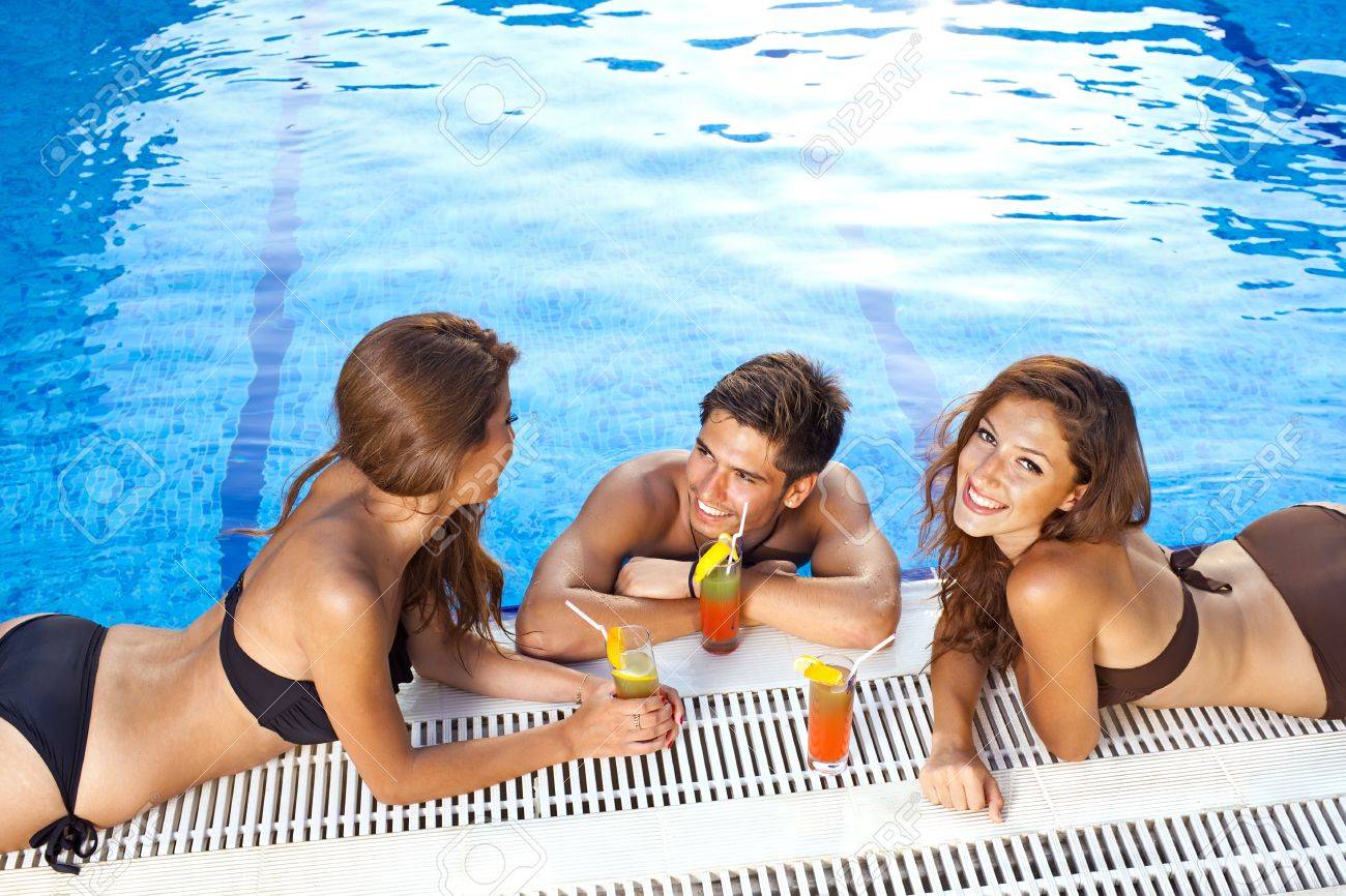 21500237-Handsome-young-man-standing-in-a-sparkling-blue-swimming-pool-chatting-to-two-beautiful-women-in-bik-Stock-Photo.jpg