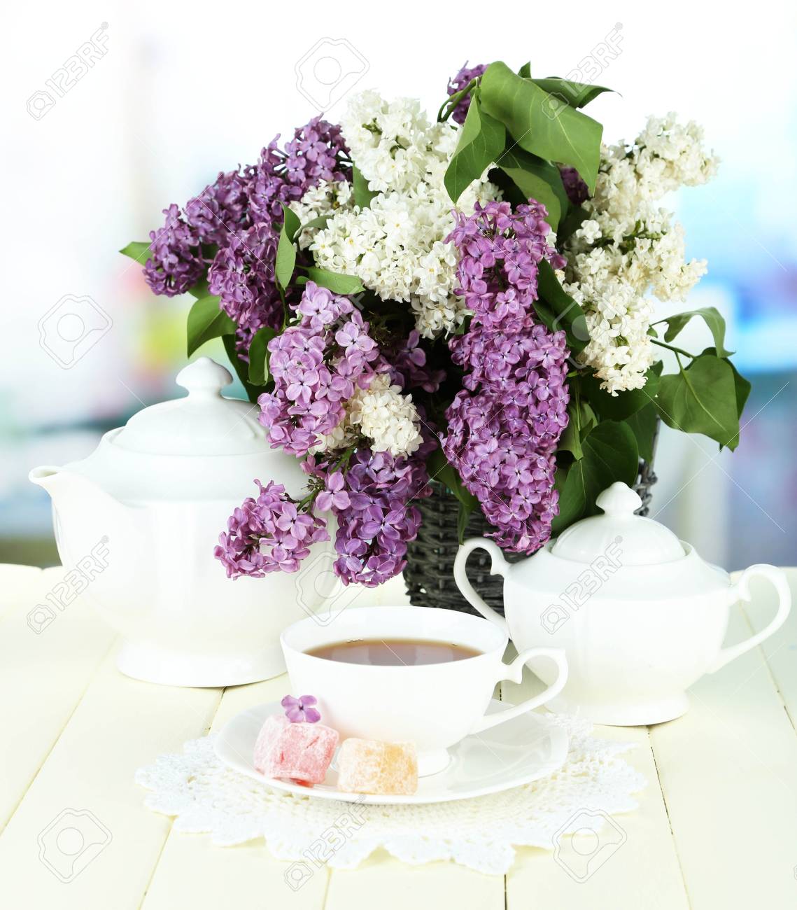 Foto de archivo , Composici?n con hermosas flores de color lila, servicio de t? en la mesa de madera sobre fondo brillante