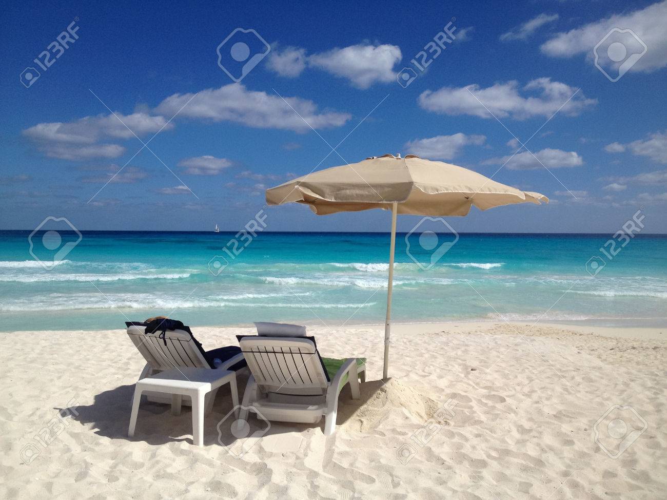 Due sedie a sdraio su una spiaggia di sabbia bianca con ombrellone ...