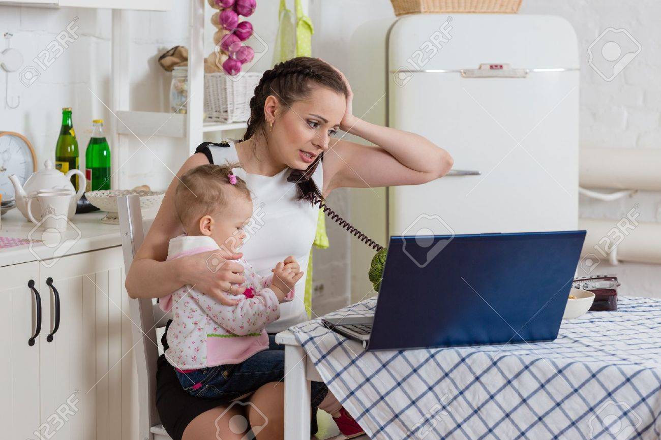 Jeune mère avec le petit enfant assis à la table à manger dans la ...