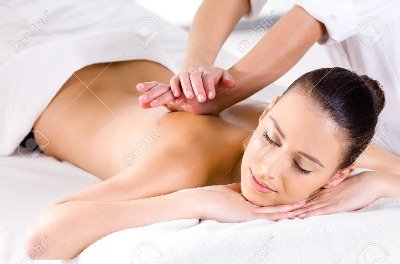 Ontspannende massage voor jonge mooie vrouw in de spa salon ... Slaapkamer donker meubilair