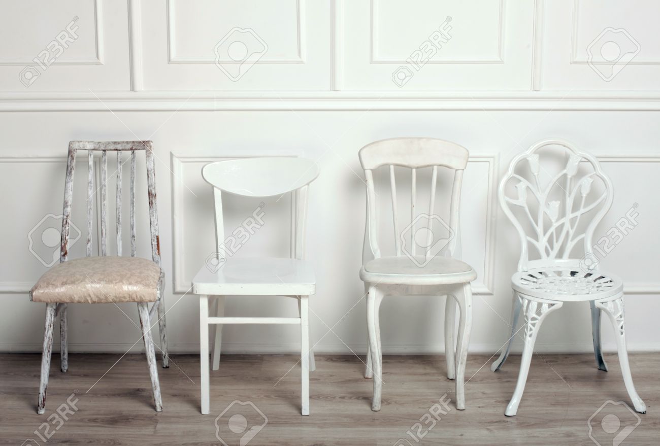 Set of white wooden vintage chairs standing in front of a white ...