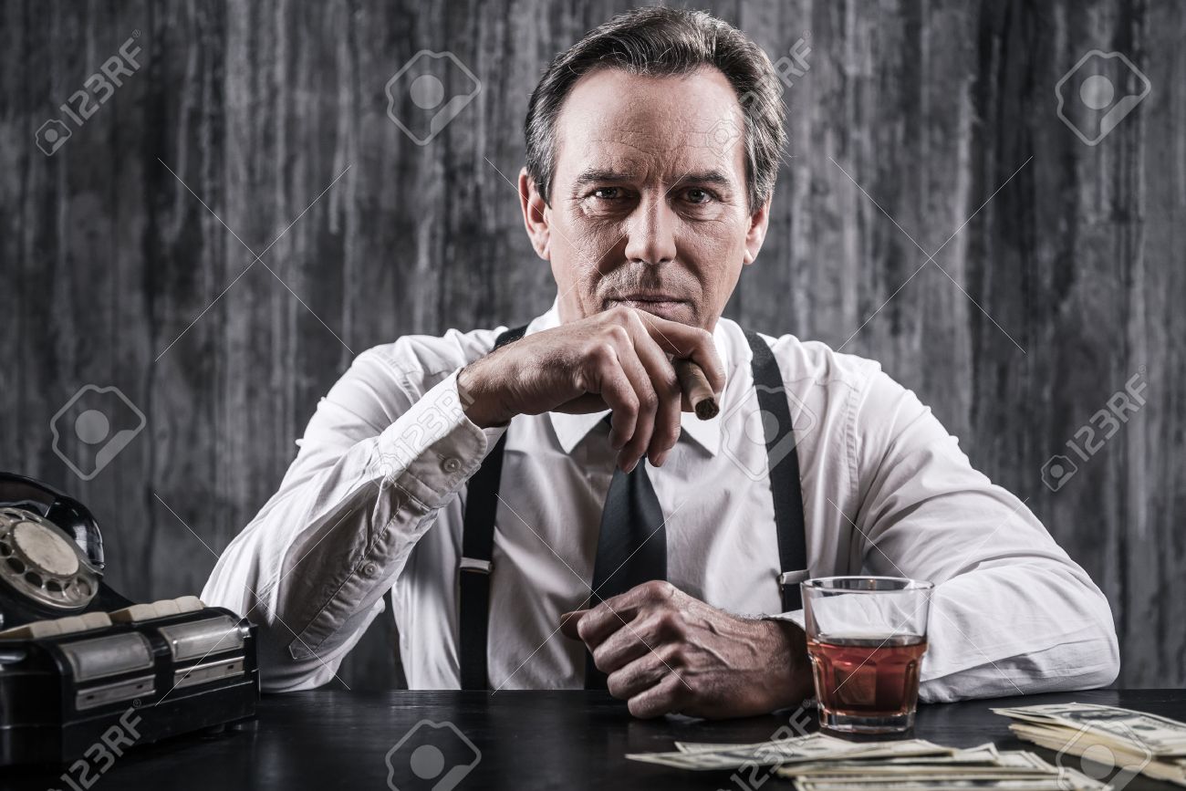 34773204-Mafia-boss-Serious-senior-man-in-shirt-and-suspenders-sitting--Stock-Photo.jpg