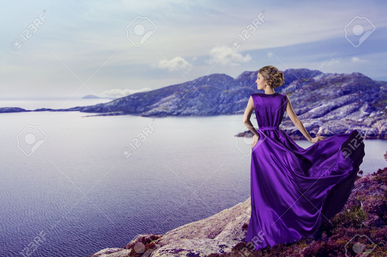 Vrouw in paars jurk op zoek naar bergen zee, zwaaien jurk vliegen ...