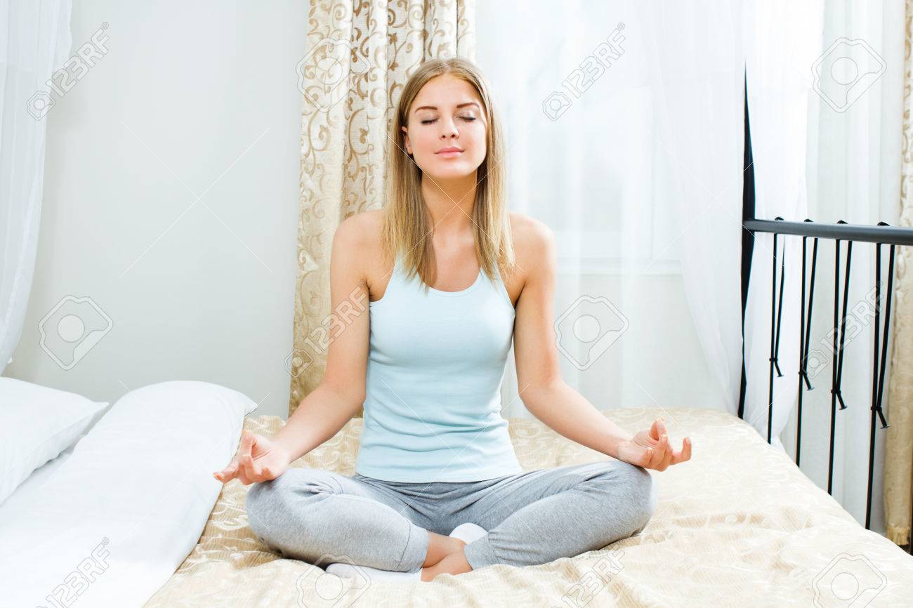 Il sesso migliora con gli ultrasuoni 27659018-Bella-donna-bionda-sta-meditando-sul-letto-nella-sua-camera-da-letto-Archivio-Fotografico