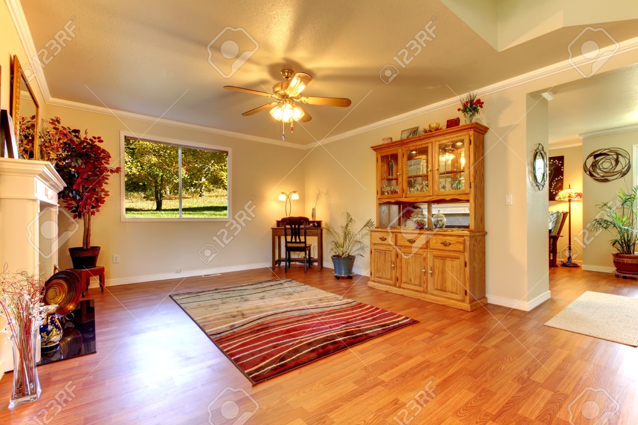 Grote woonkamer met houten vloer, rood tapijt en beige muren ...