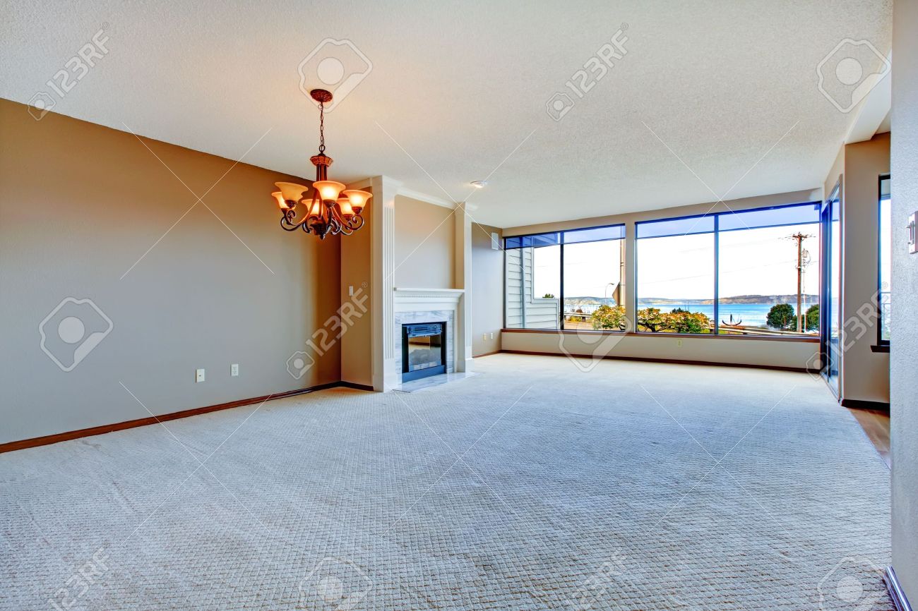 Appartement woonkamer met grote ramen, tapijt en hardhouten vloer ...