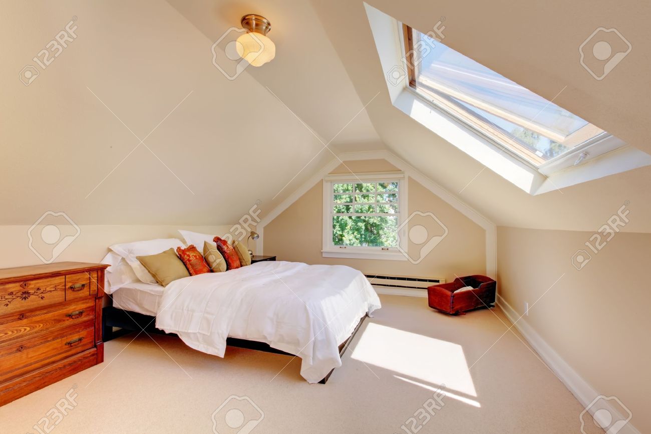 Chambre mansardée avec un lit moderne blanc et des murs beige et ...