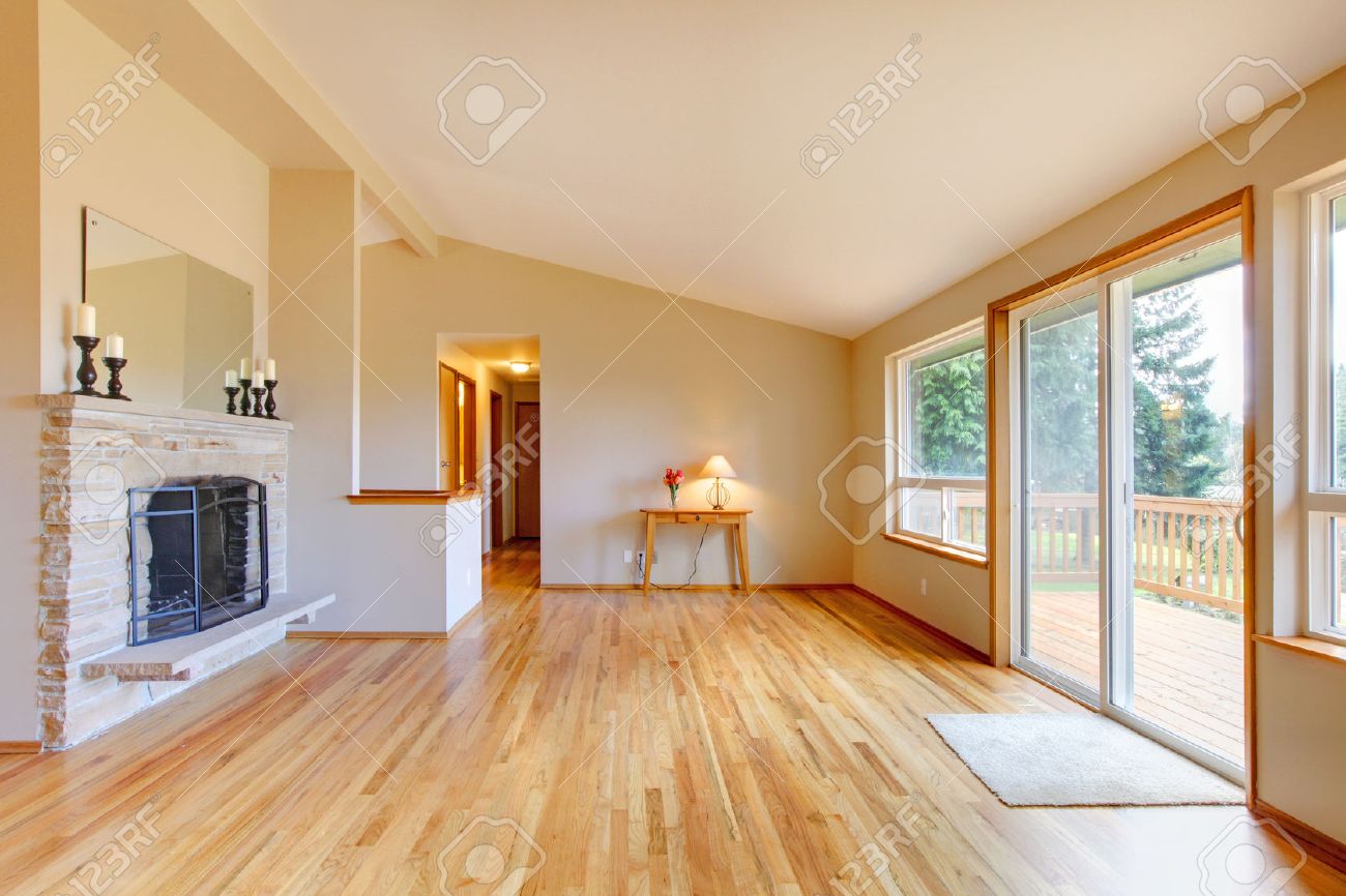 Lege woonkamer met een open haard, hardhouten vloer en glazen ...