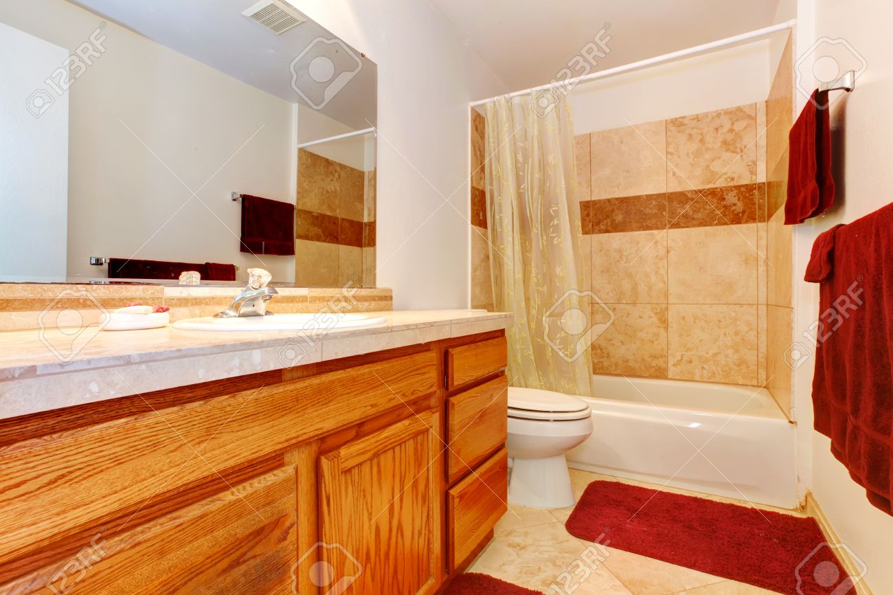 Bagno beige con pavimento di piastrelle, mobili in legno, teli ...