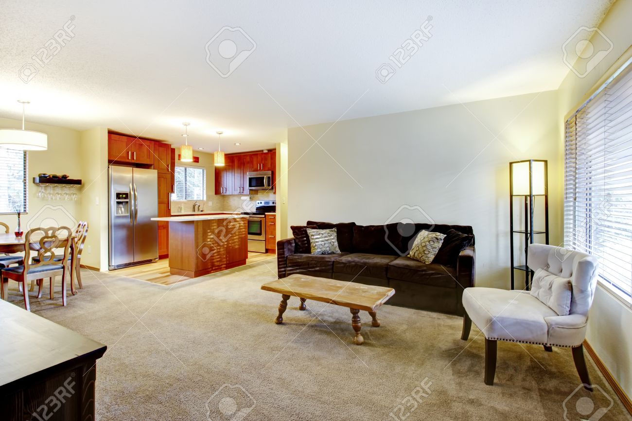 Lichte muur woonkamer met beige vloerbedekking, bruine bank ...