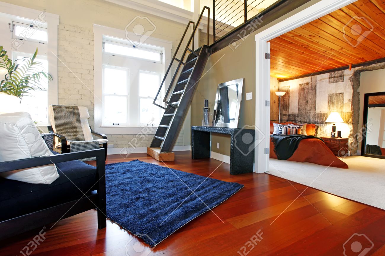 Salon moderne avec mur de briques peint, plancher de bois franc et ...