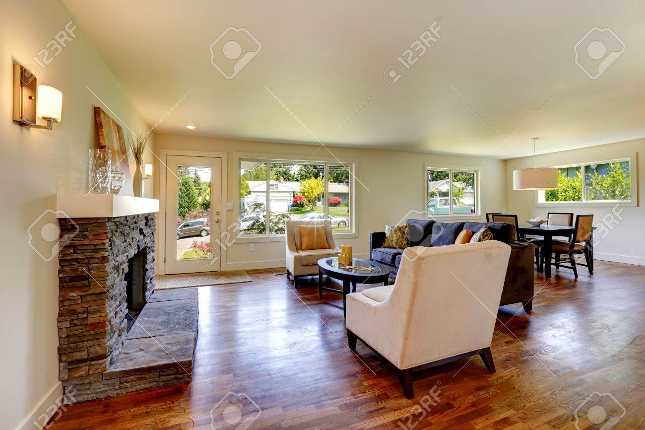 Woonkamer met stenen achtergrond open haard, bank, stoelen en een ...