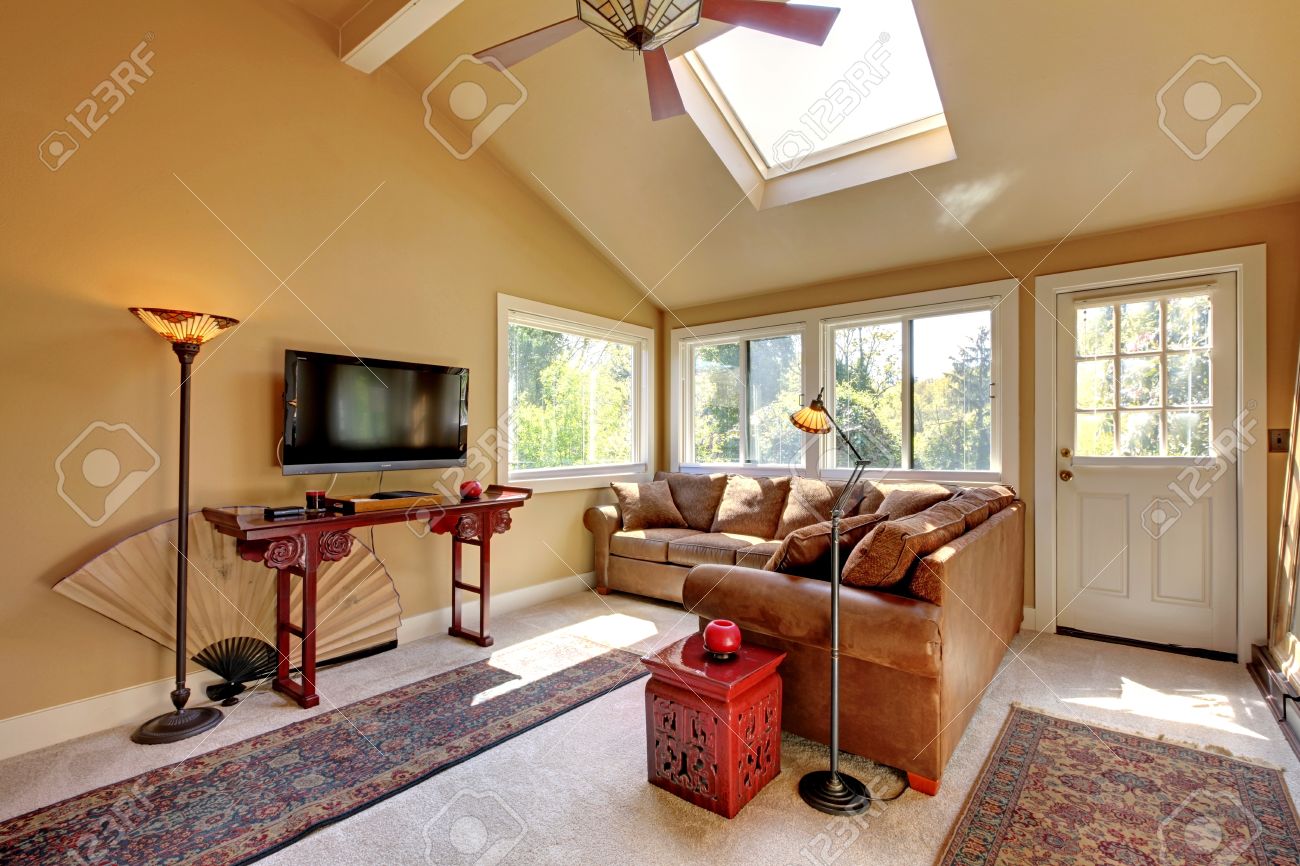 Grote woonkamer met een bank, tv en bruine muren met beige ...