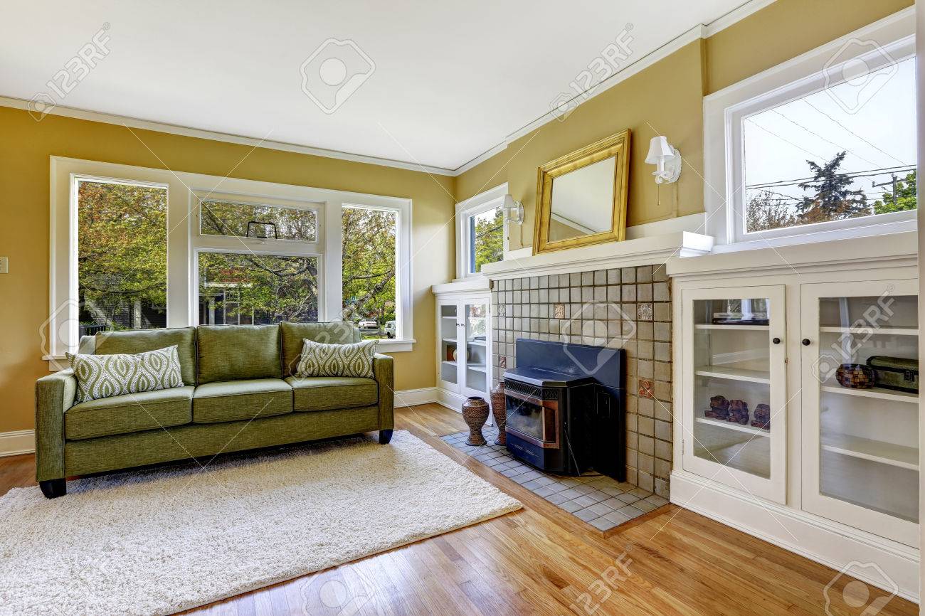 Licht geel woonkamer met open haard, groene bank en witte kasten ...