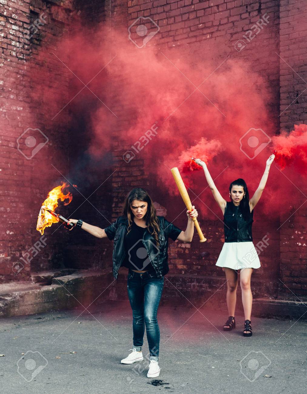 33725696-Two-Bad-girls-with-Molotov-cocktail-and-red-smoke-bomb-in-the-street-Outdoor-lifestyle-portrait-Stock-Photo.jpg