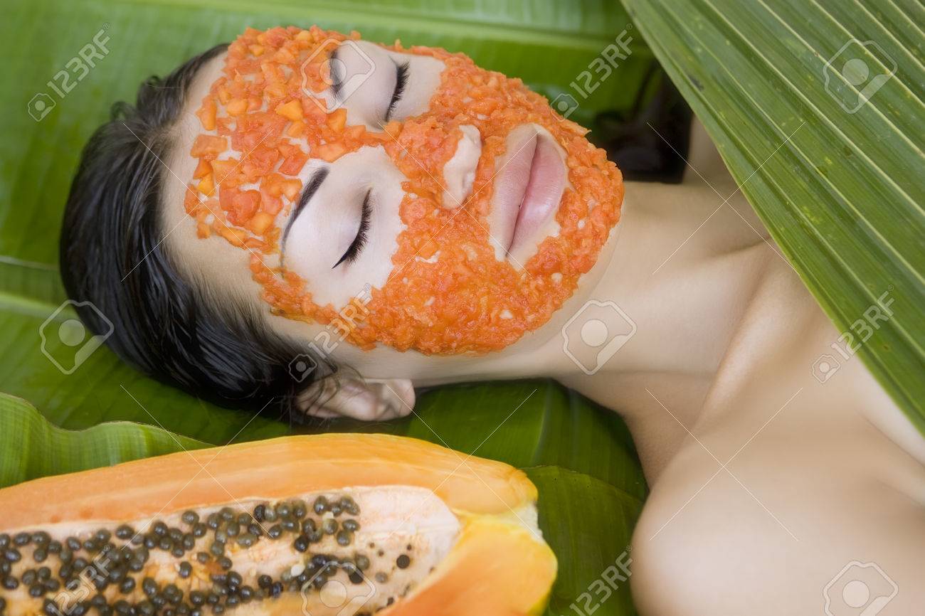 Mooie blanke vrouw met verse papaya natuurlijke gezichtsmasker ... Slaapkamer donker meubilair
