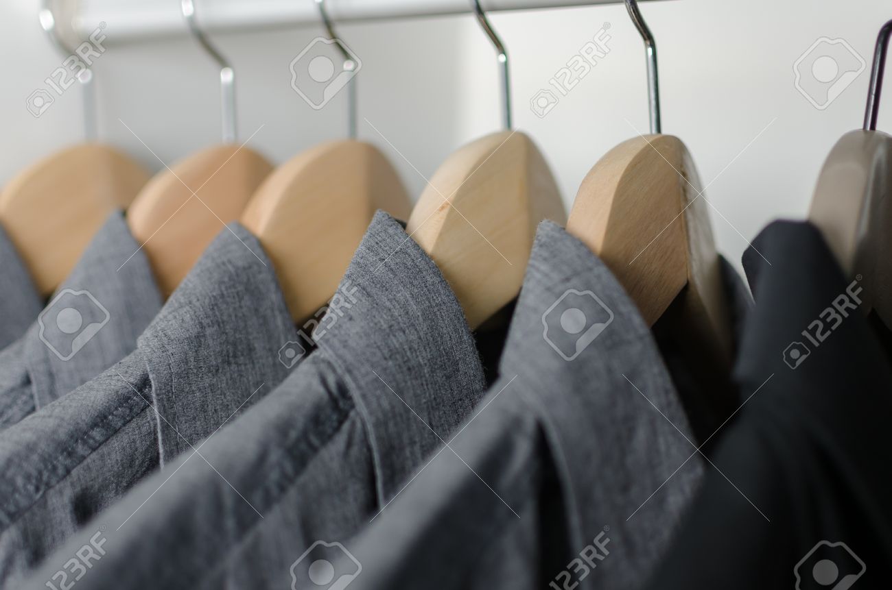 Vicino fila di camicie grigie e nere appesi su attaccapanni a muro ...