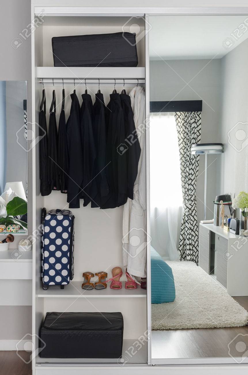 Fila di camicie nere appesi su attaccapanni a muro bianco foto ...