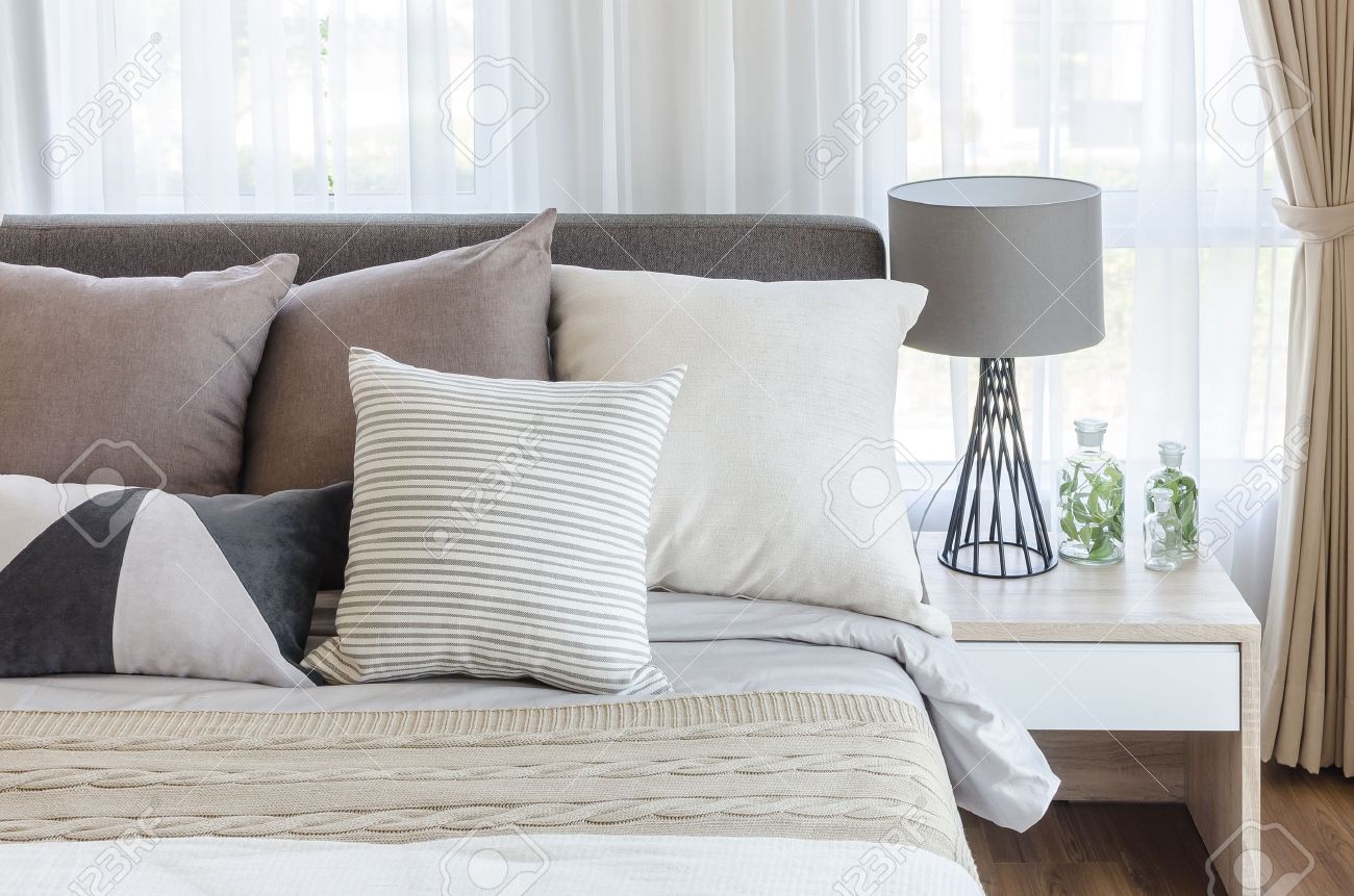 Modern stil sovrum med kuddar på sängen och modern grå lampa på ...