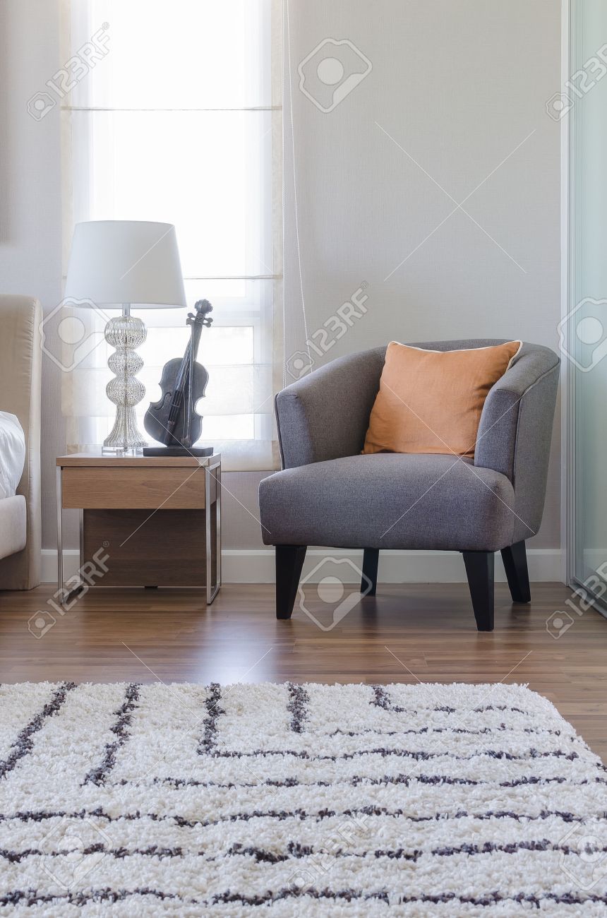 Banque dimages orange oreiller sur la chaise gris moderne avec table de chevet et lampe blanche dans la chambre ã la maison