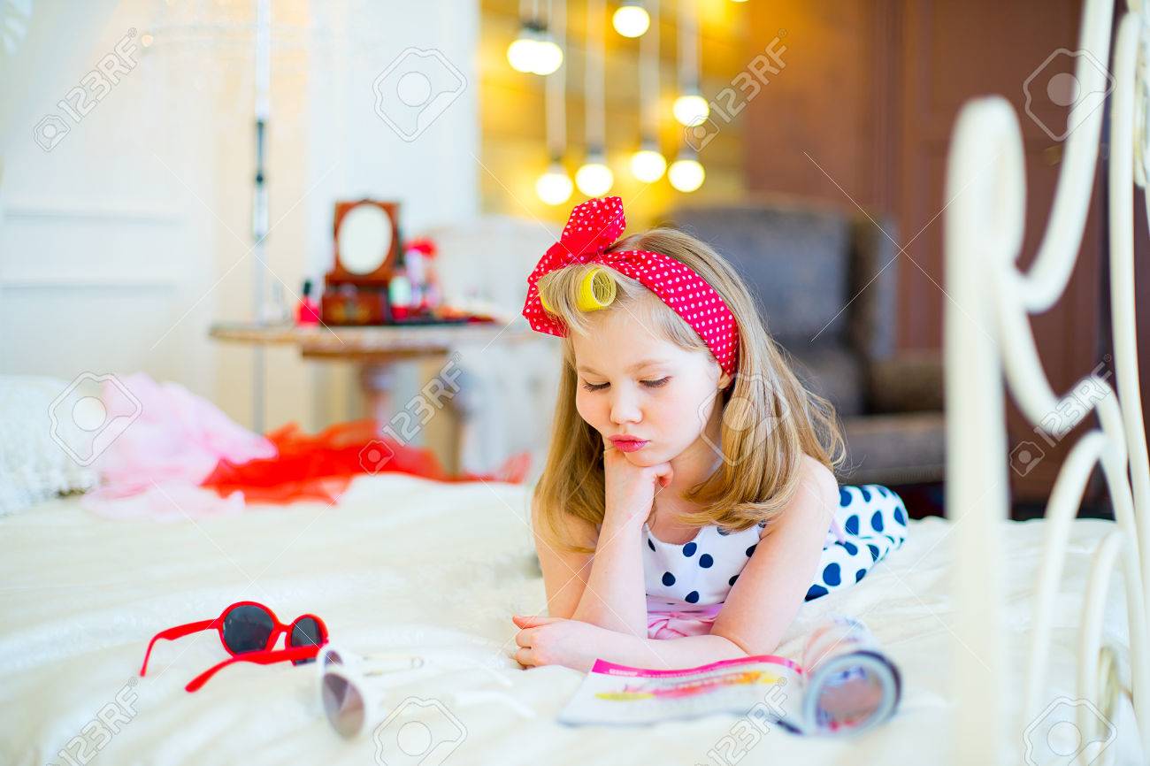 La bambina pone in stile pin up su un letto con gli occhiali da ...