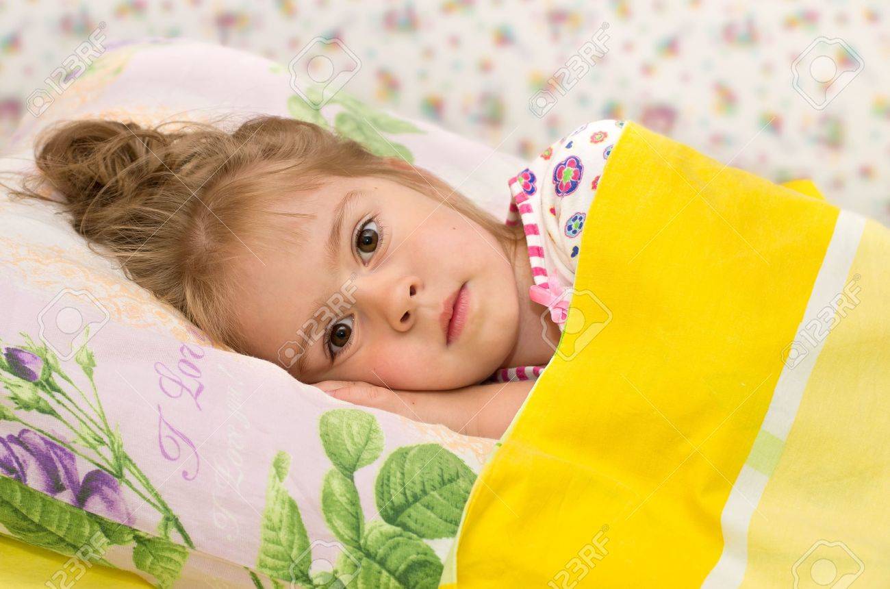 La bambina a letto. una bambina a letto con gli occhi tristi foto ...