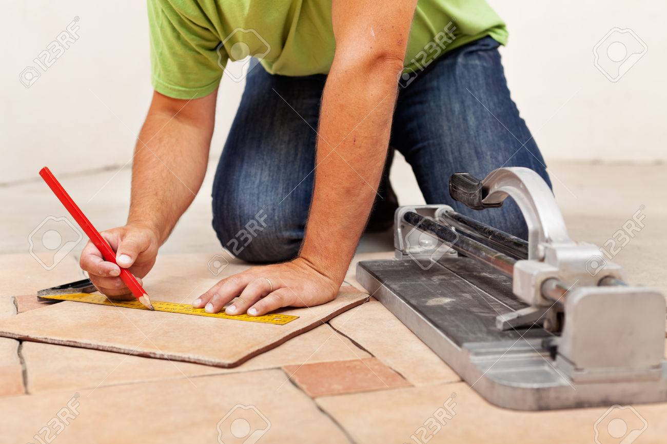 Worker Hands Laying Ceramic Floor Tiles - Measuring And Marking Worker Hands Laying Ceramic Floor Tiles - Measuring And Marking