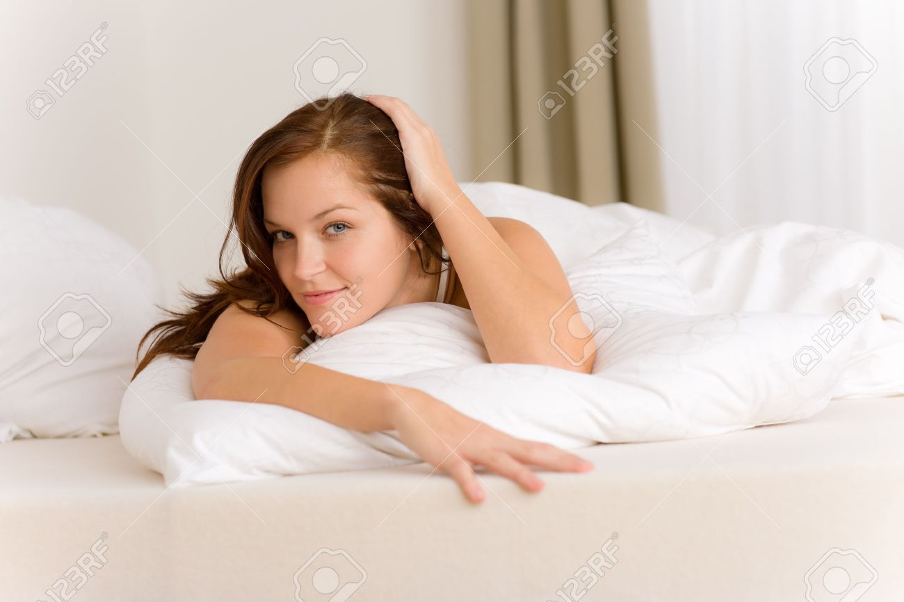 Chambre à coucher femme heureuse dans le lit de couleur blanche ...