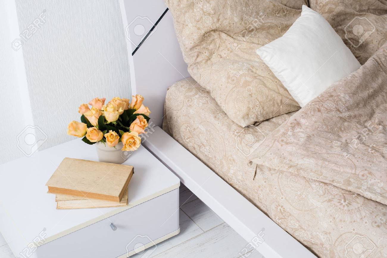 Ljust vit sovrum inredning, mysig säng med beige linne, blommor på ...
