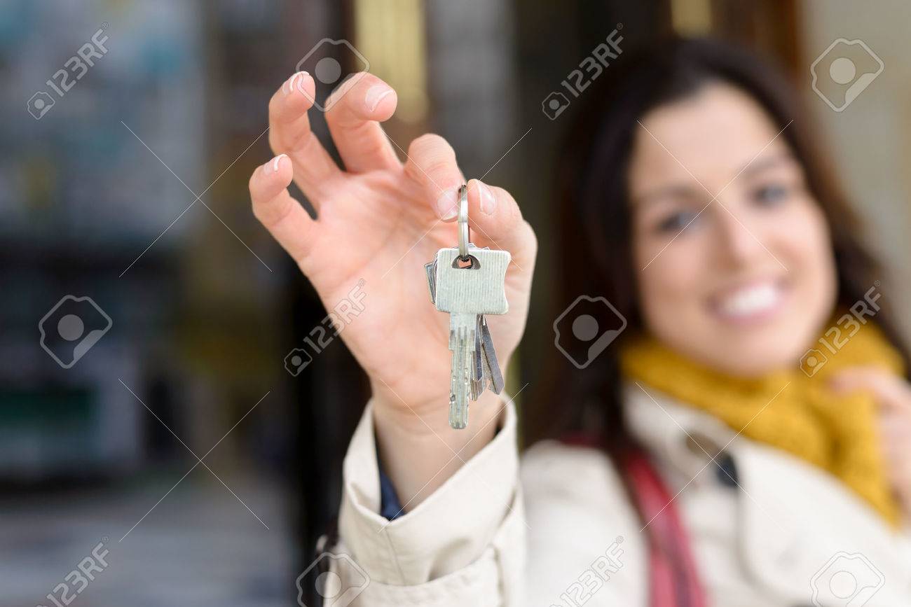 Apartment Building Ownership woman holding home keys outside from apartment building. rental Apartment Building Ownership woman holding home keys outside from apartment building. rental