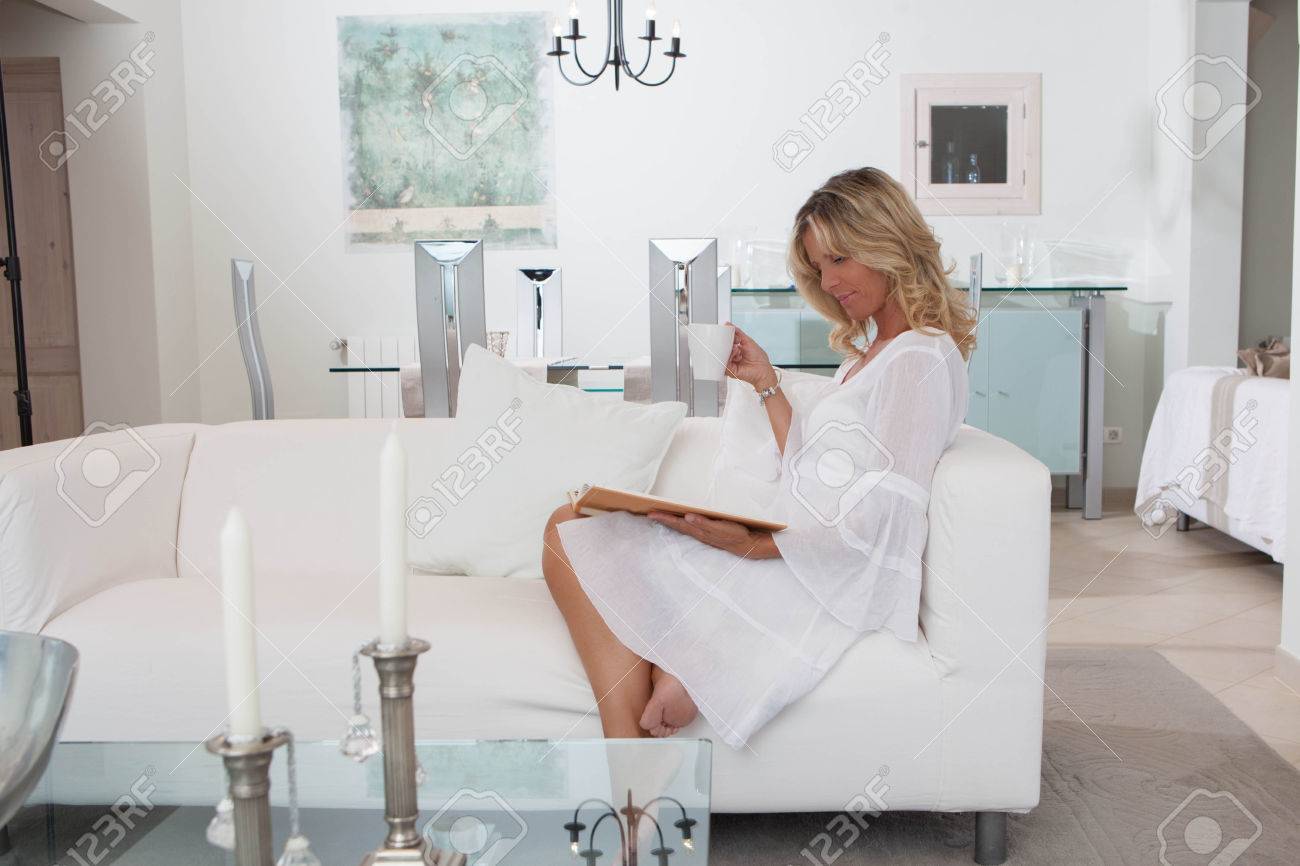 Femme chic dans la chambre blanche boire café livre de lecture ou ...