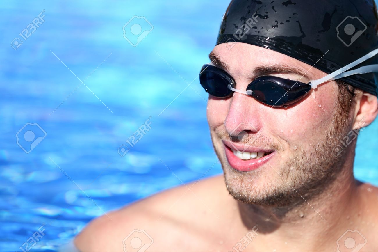 12611592 Male Swimmer Portrait Man swimming model smiling happy wearing swimming goggles and swim cap in pool Stock Photo
