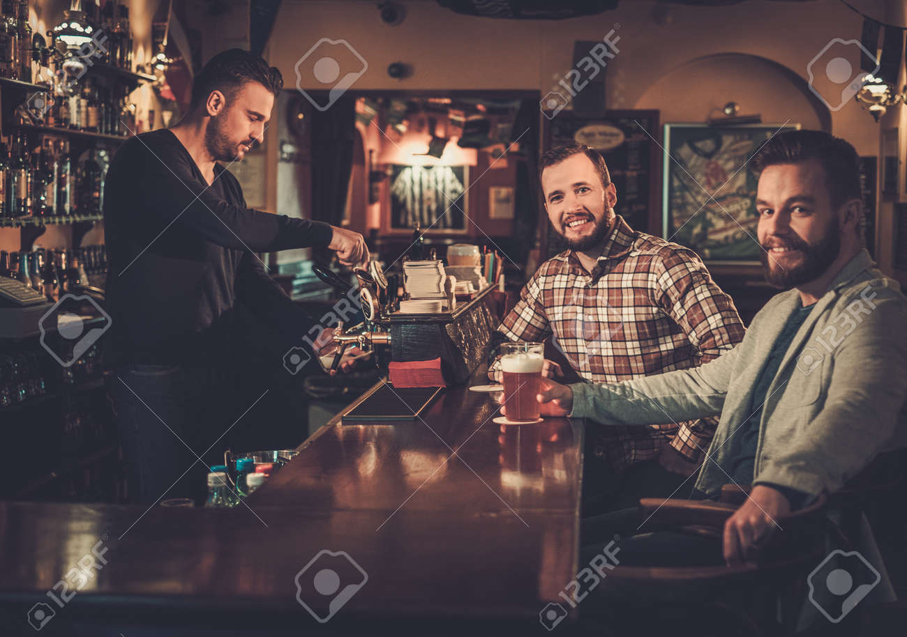 Vecchi amici allegri che bevono birra alla spina al bancone bar ... Bancone bar falegnameria