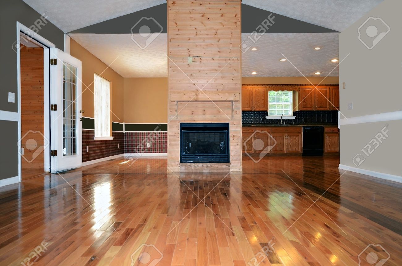 Een lege woonkamer met een open haard. daarachter is de eetkamer ...