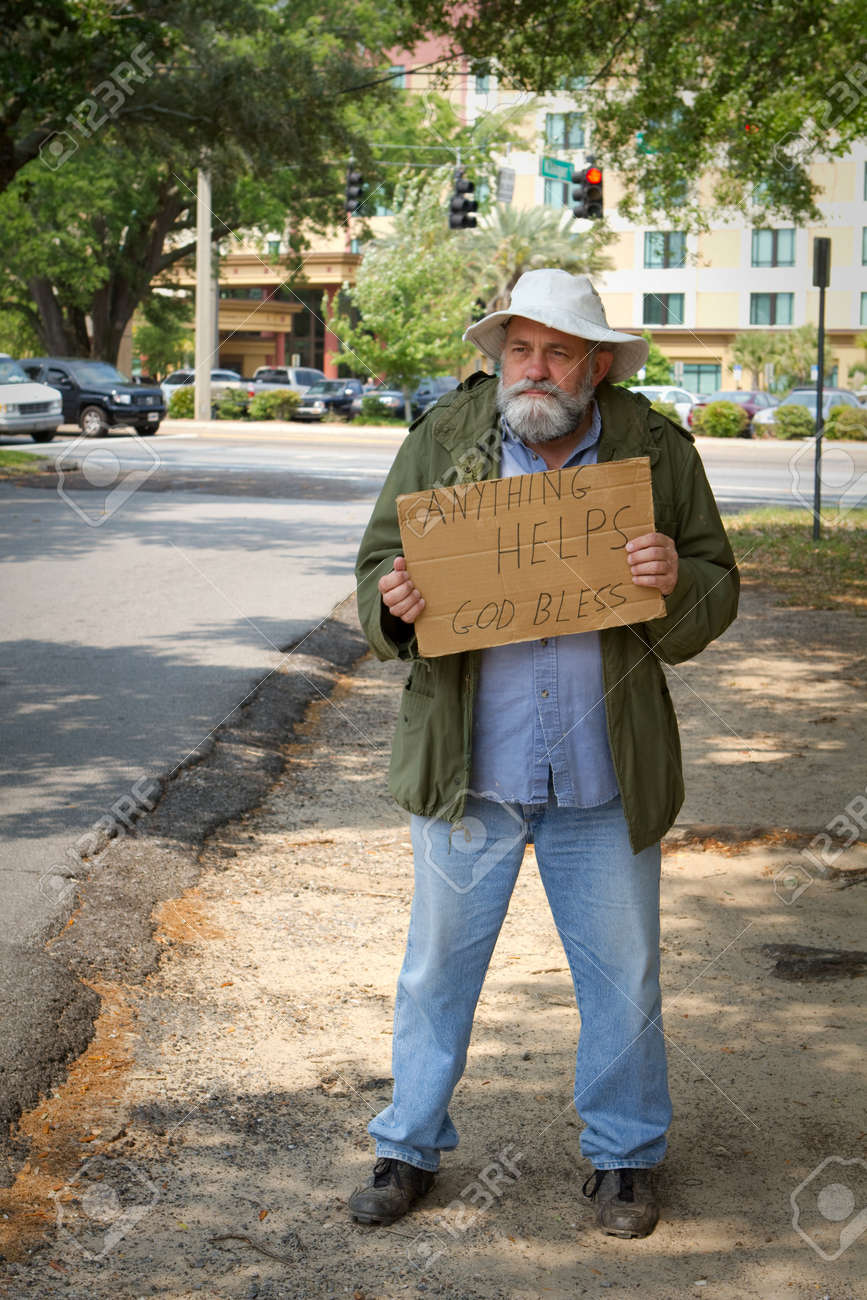 9485846-Disheveled-homeless-man-stands-by-the-side-of-the-road-begging-for-help-by-holding-a-sign--Stock-Photo.jpg