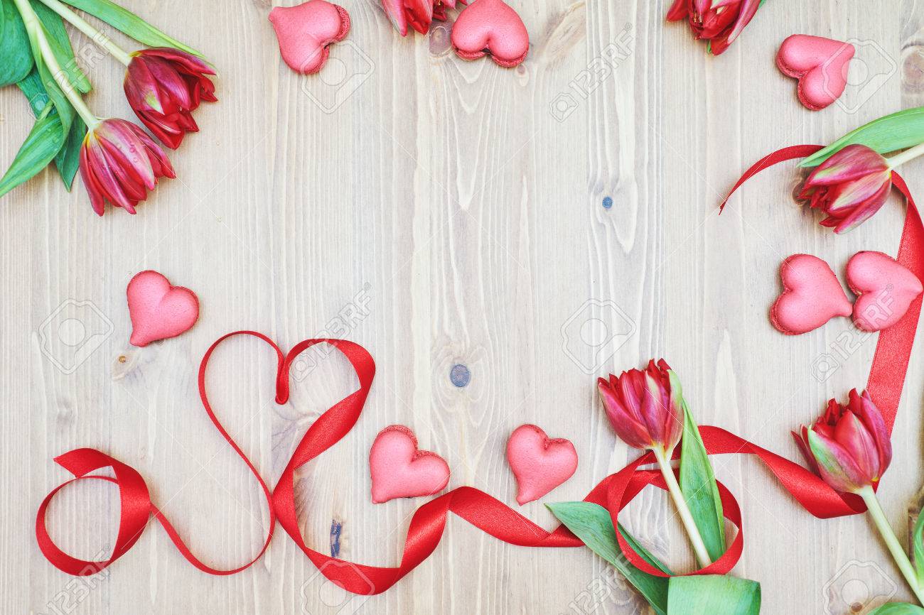 Amaretti a forma di cuore con fiori e nastro su un tavolo di legno ...
