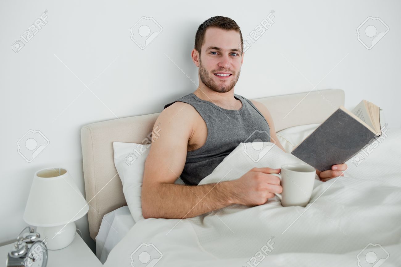 Junger mann einen roman zu lesen, während sie einen kaffee trinken ... Schlafzimmer mann