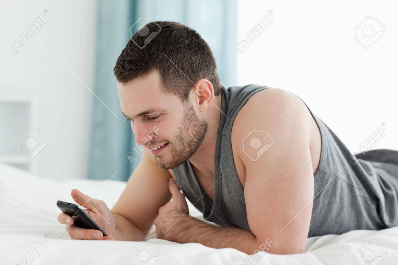 Junger mann mit seinem handy in seinem schlafzimmer lizenzfreie ... Schlafzimmer mann