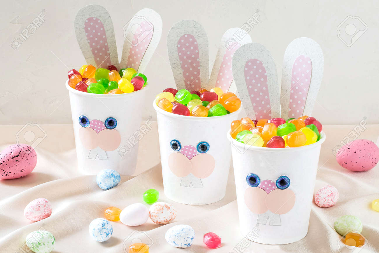 お菓子と面白いイースターのウサギの形で紙コップ 紙コップに自家製のアップリケ 子供のギフトのためのアイデア イースターの祭典のための Diy のコンセプト の写真素材 画像素材 Image