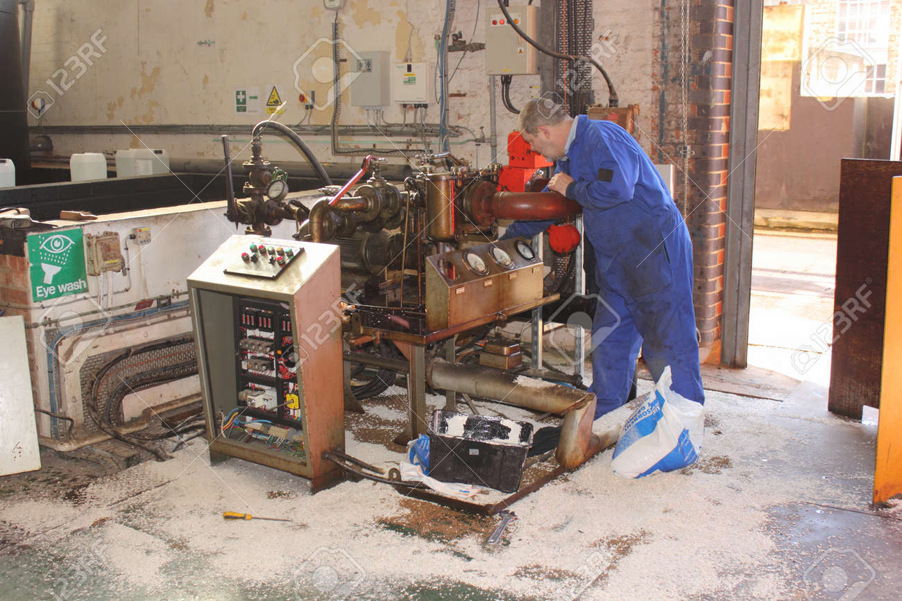 a diesel fuel spill in a boilerhouse being cleaned by an engineer wearing his ppe using