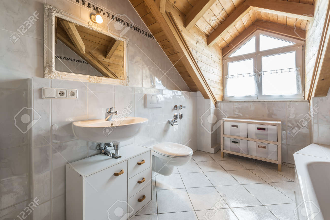 archivio fotografico bagno di un appartamento in mansarda con lavandino specchio luce finestra wc vasca da bagno armadi in legno e soffitto