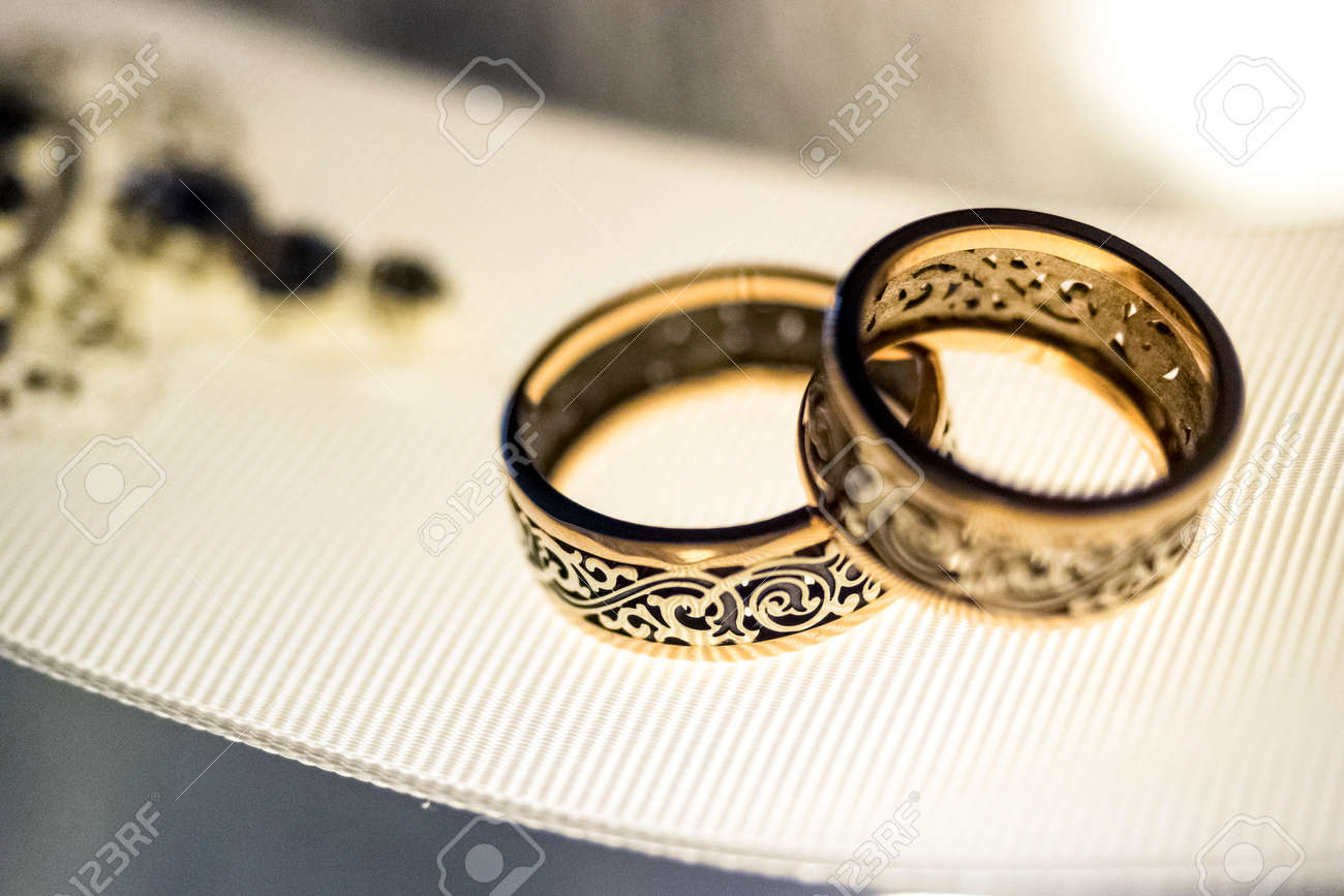 Anillos De Bodas De Oro Con Un Diseño Raro En La Ancha Cinta Blanco De Cerca Fotos, Retratos, Imágenes Y Fotografía De Archivo Libres De Derecho. Image 56046794.