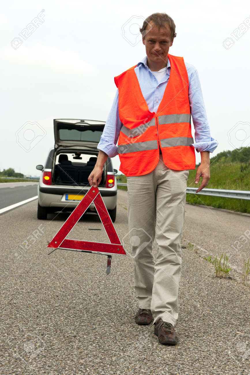 Man Walking Backwards From His Car Wearing A Safety Vest, Carying A Warning  Triangle Stock Photo, Picture and Royalty Free Image. Image 10097591., image size:867x1300