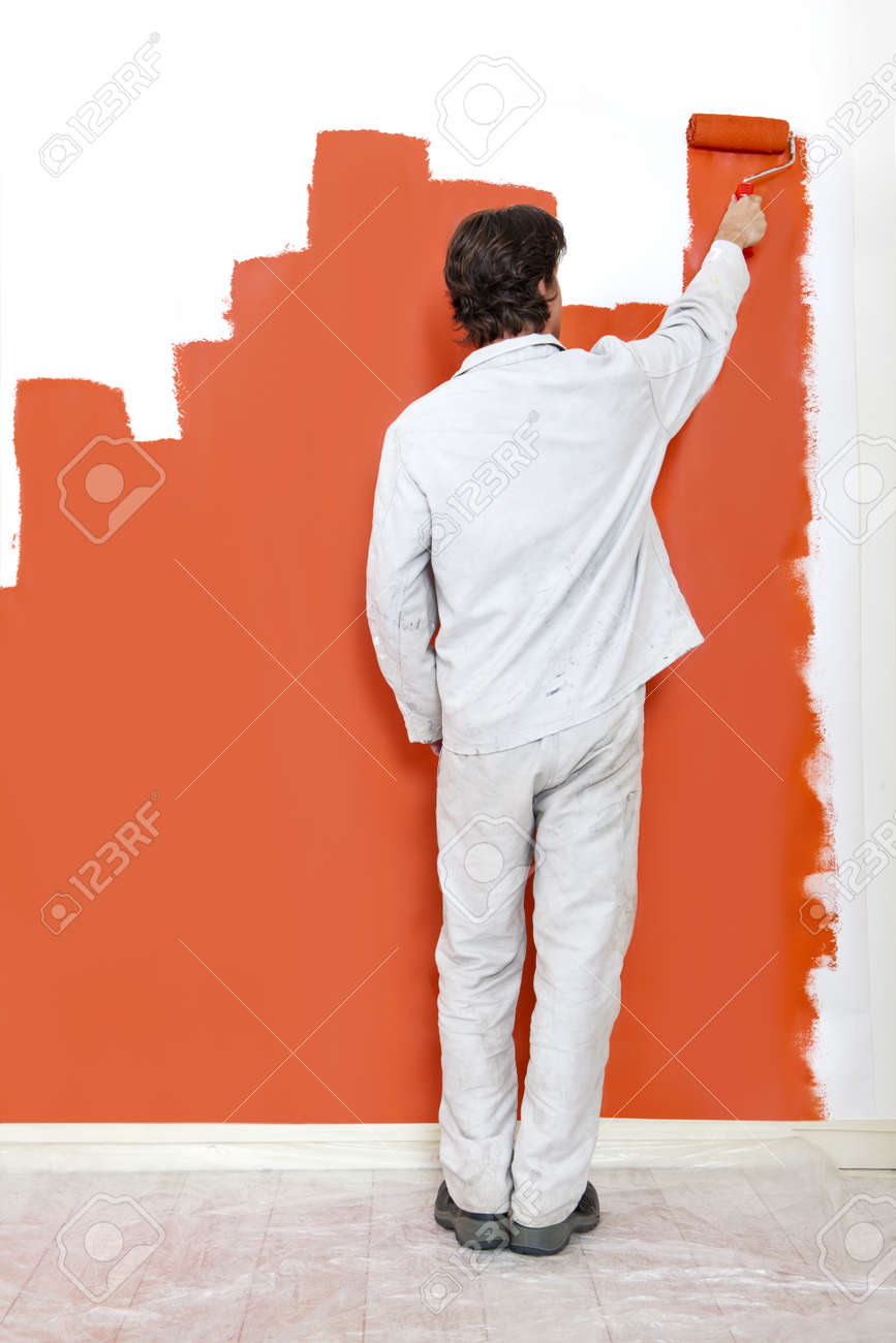 Man Painting A Wall With Orange Paint And Roller Stock Photo Man Painting A Wall With Orange Paint And Roller Stock Photo