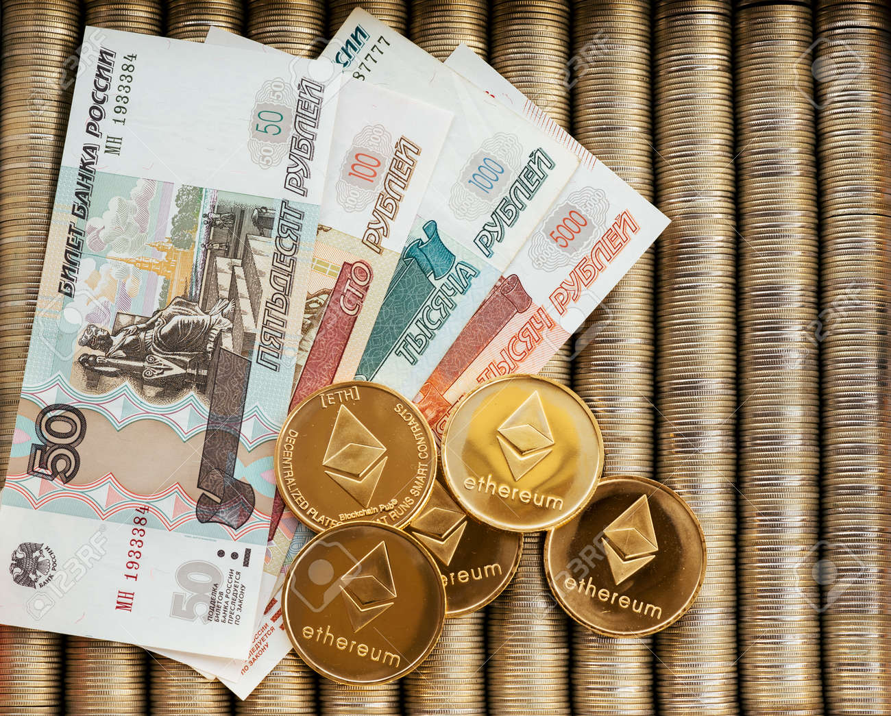 러시아 루블의 종이 액면가인 금 암호화폐 이더리움 ETH. 금속 동전은 서로 부드러운 배경에 배치되어 있고 위에서 가까이에서 볼 수  있으며 암호화폐 화폐 교환이 가능합니다. 로열티 무료 사진, 그림, 이미지 그리고 스톡포토그래피. Image